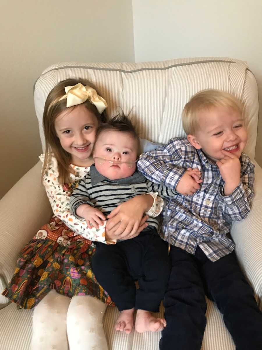 Oldest sister sits in chair with brother with down syndrome in her lap beside her other brother