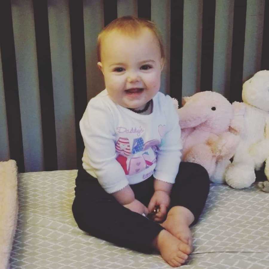 Baby girl smiles as she sits in crib at home before she passed away