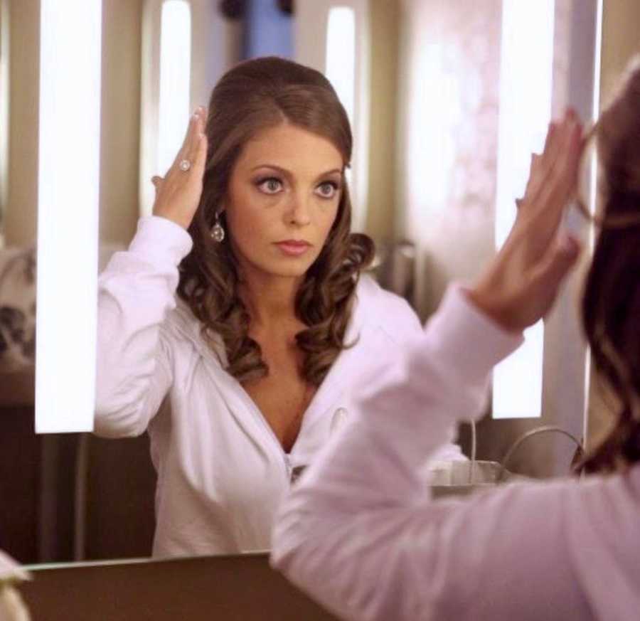 Woman about to get married sits in front of mirror fixing her hair