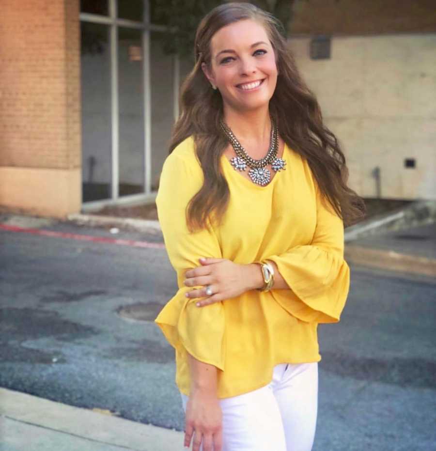 Woman who struggles with anxiety and depression stands smiling outside in parking lot