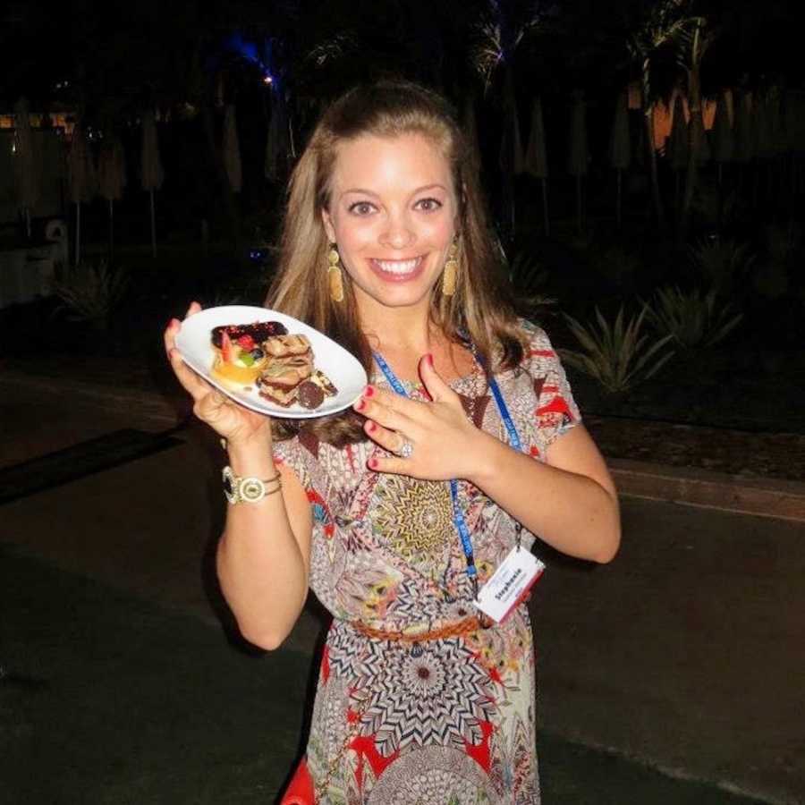 Woman who says she was a compulsive exerciser stands smiling while holding plate of desser