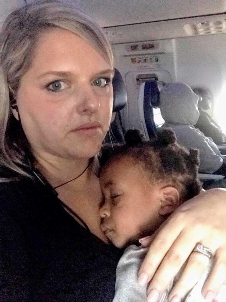 Woman takes selfie on plane while her daughter lays asleep in her lap