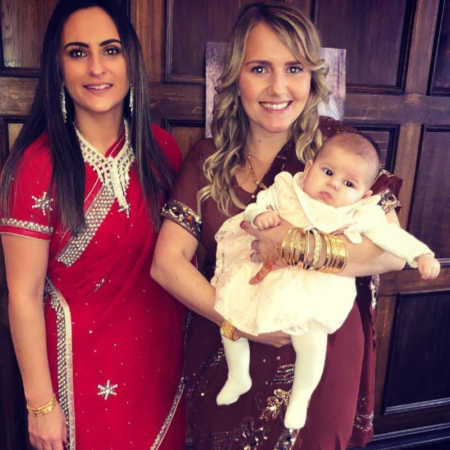 Woman stands holding her baby daughter beside her wife
