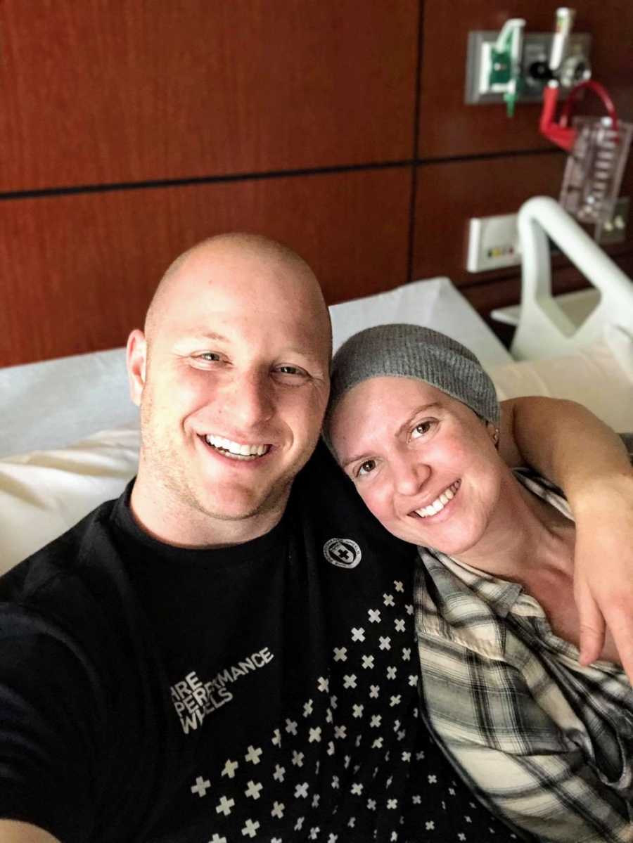 Man smiles in selfie in hospital bed beside wife who is undergoing chemotherapy