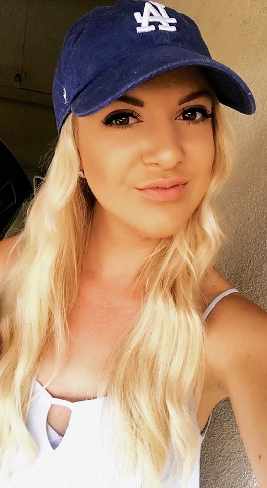 Young woman smiles in selfie as she wears LA Dodger's hat
