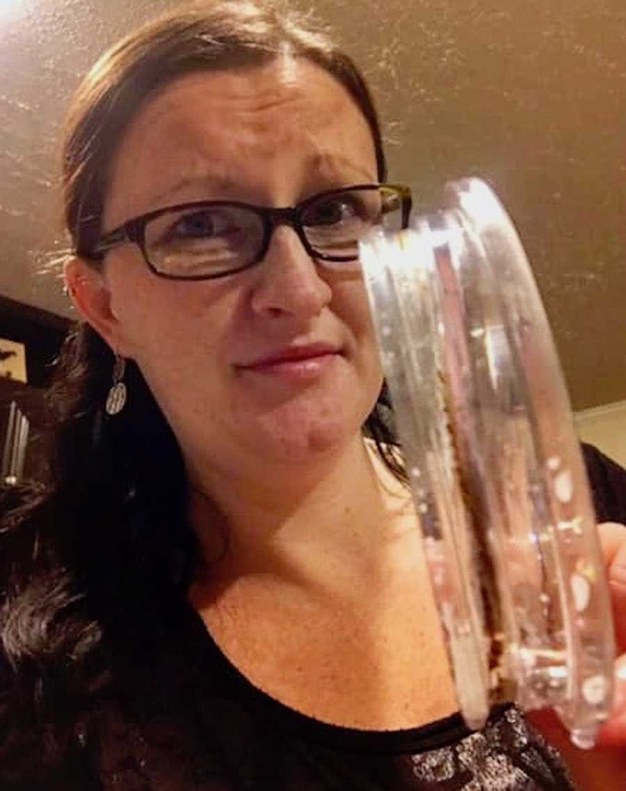 Woman makes concerned face in selfie and she holds up reusable plastic lid with mold on it