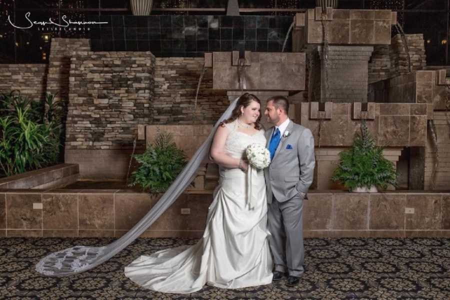 Bride and groom stand smiling as they look into each others eyes