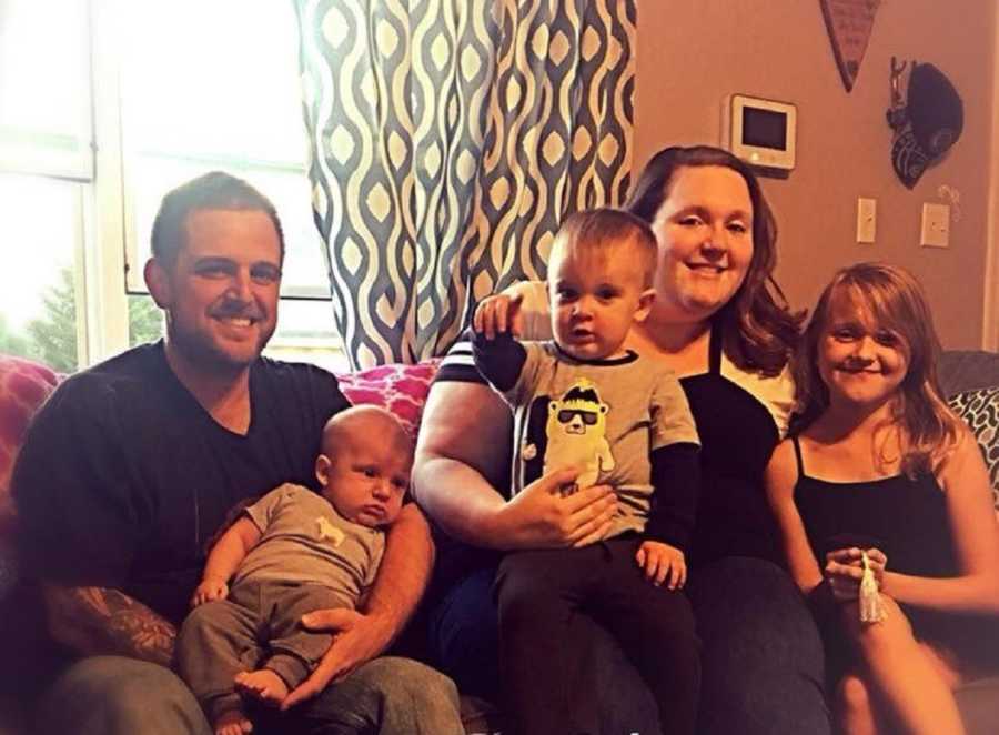 Woman who was sexually abused by her father when she was a child sits on couch with three kids and husband