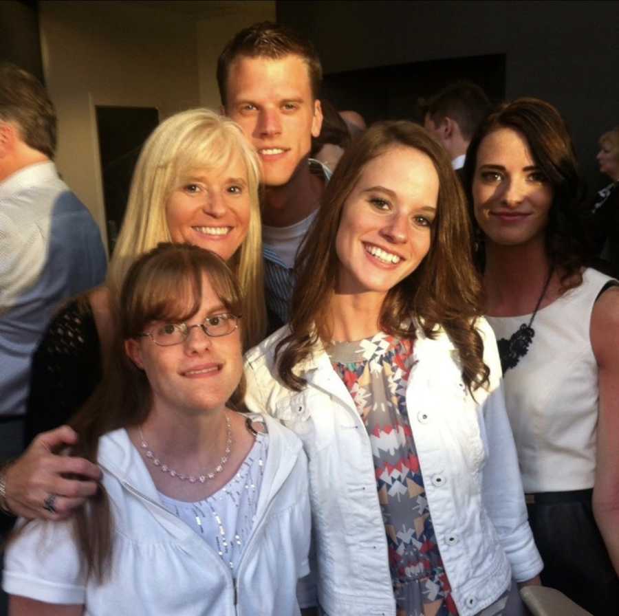 Widow stands smiling beside her four kids