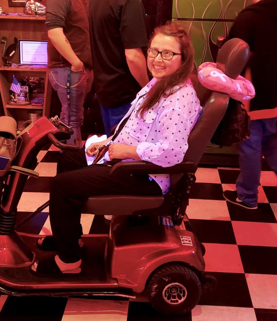 Woman whose cancer has spread, sits smiling in electric scooter