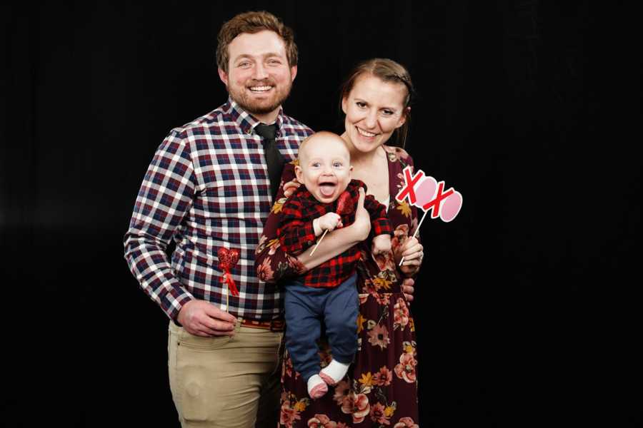 Man who was bullied as a kid stands smiling with wife and son for photoshoot