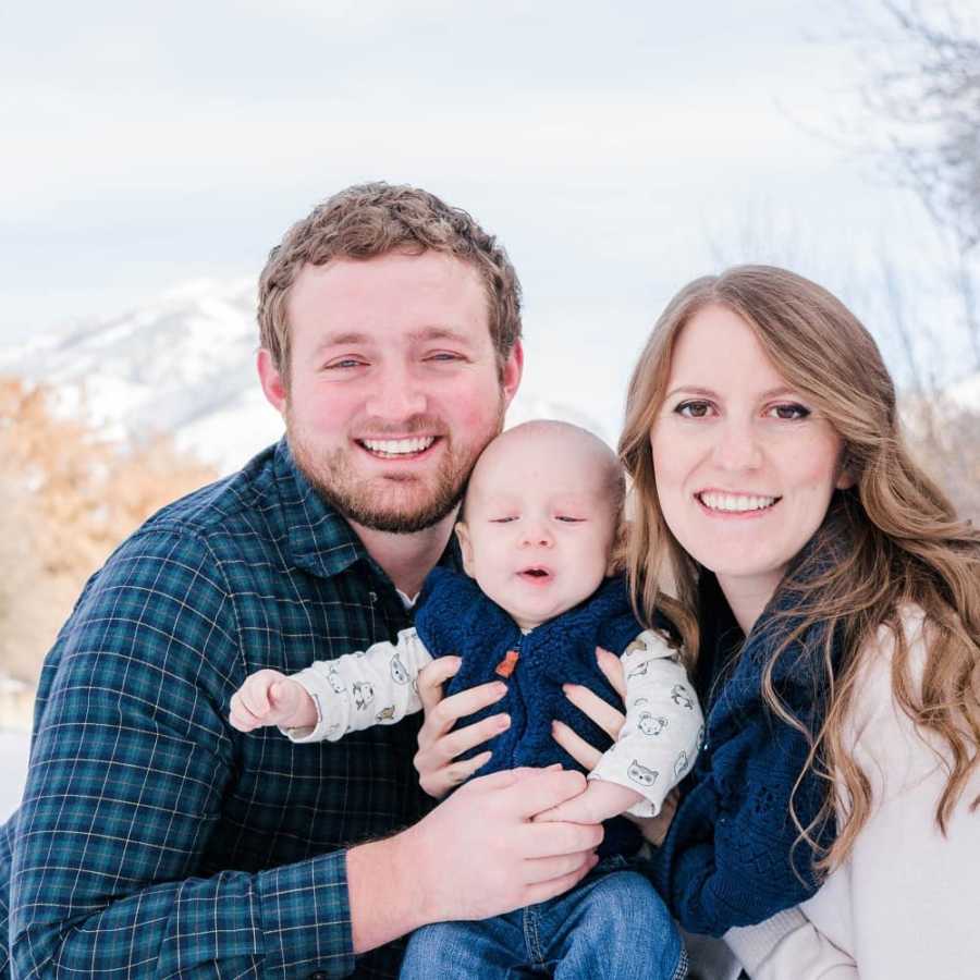 Man who was bullied as a child smiles as he holds his baby beside his wife