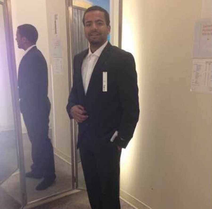 Man who is drug addict stands in fitting room wearing suit