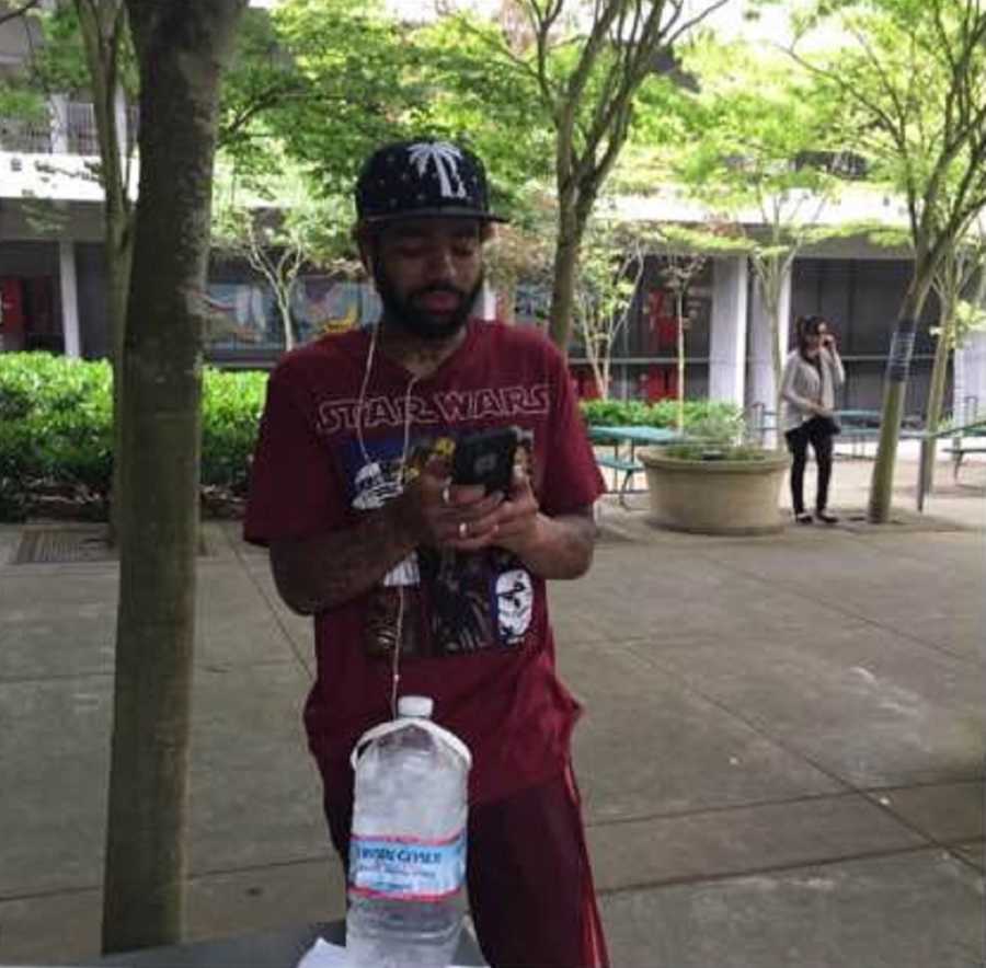 Man who is addicted to drugs stands on sidewalk on phone