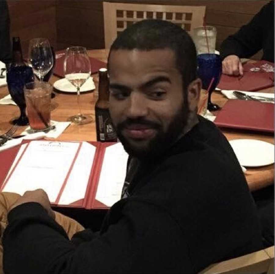 Man sits at restaurant table smiling as he looks over his shoulder