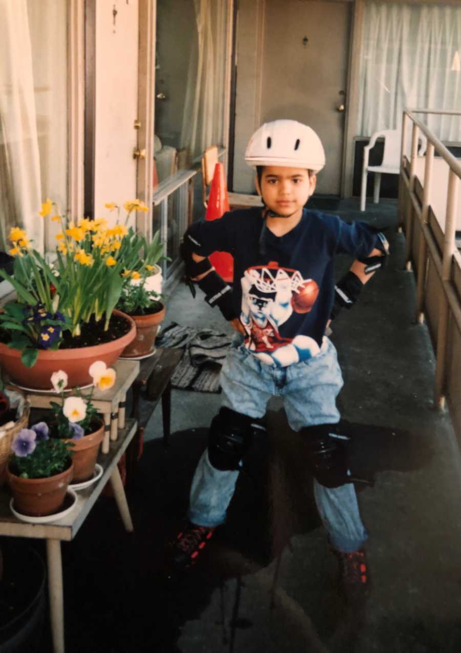 Little boy stands with hands on his hips as he wears helmet and roller blades