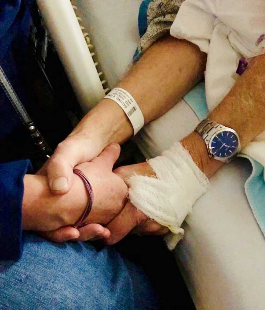 Man who lays in hospital bed after having pace maker put in holds hands with his daughter