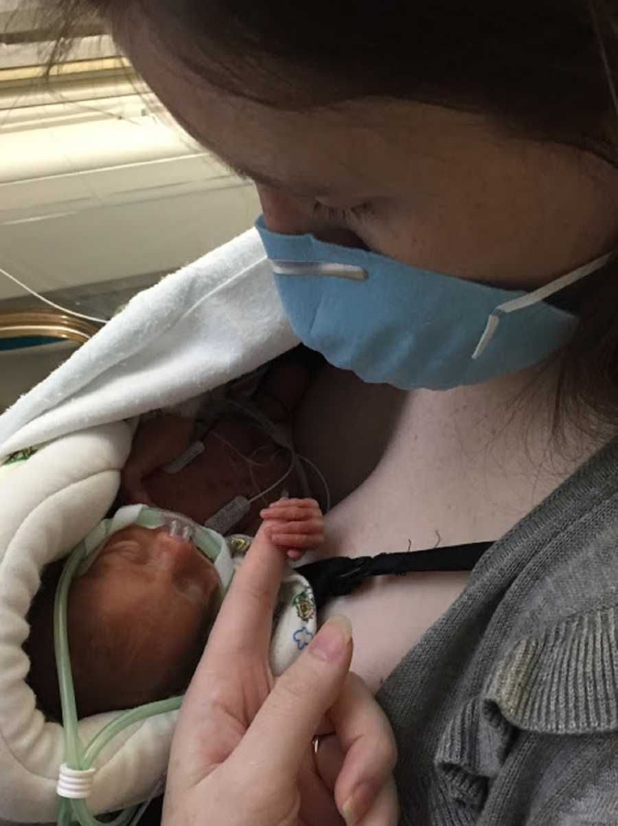 Mother wears mask as she holds intubated preemie in her arms