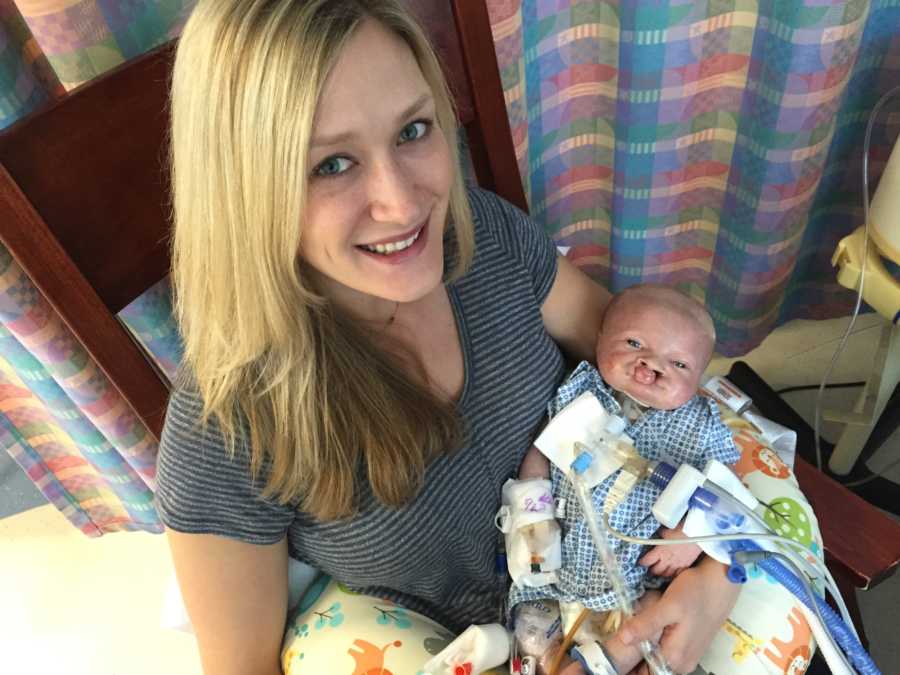 Woman smiles as she sits in NICU with her newborn who is on feeding tube