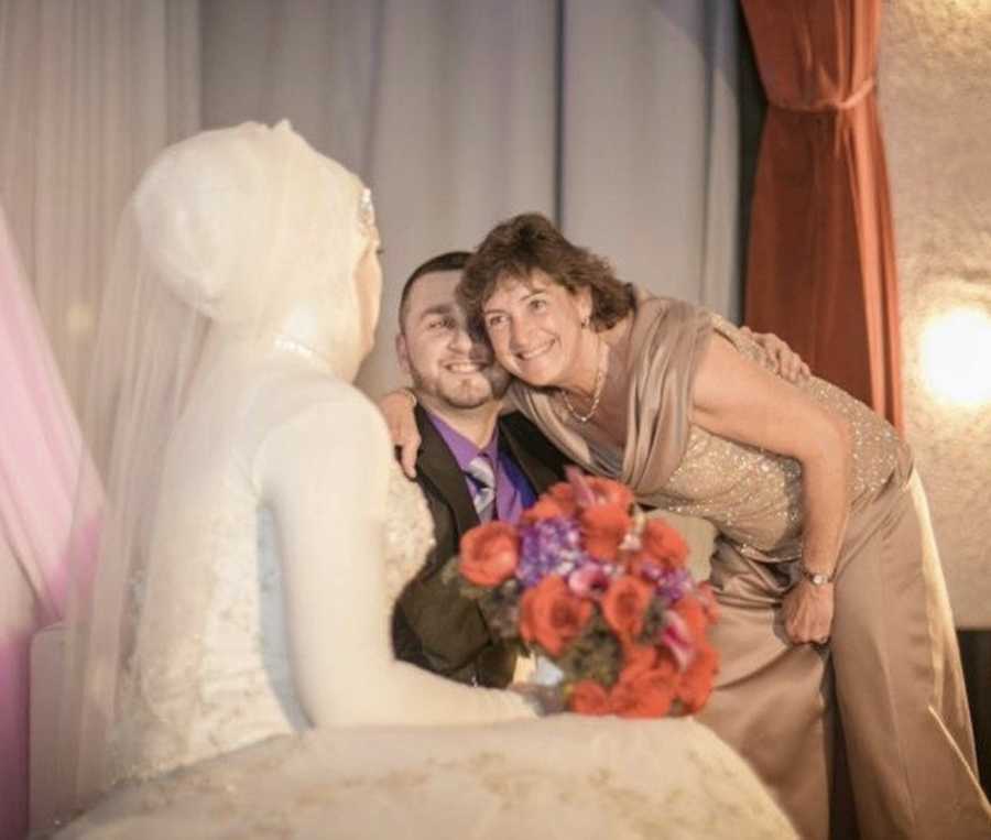 Bride looks over to see her mother hug groom