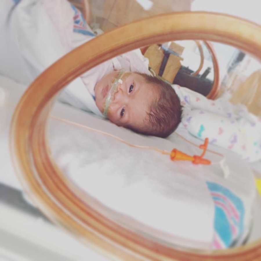 Intubated baby lays on back in NICU looking over at her side