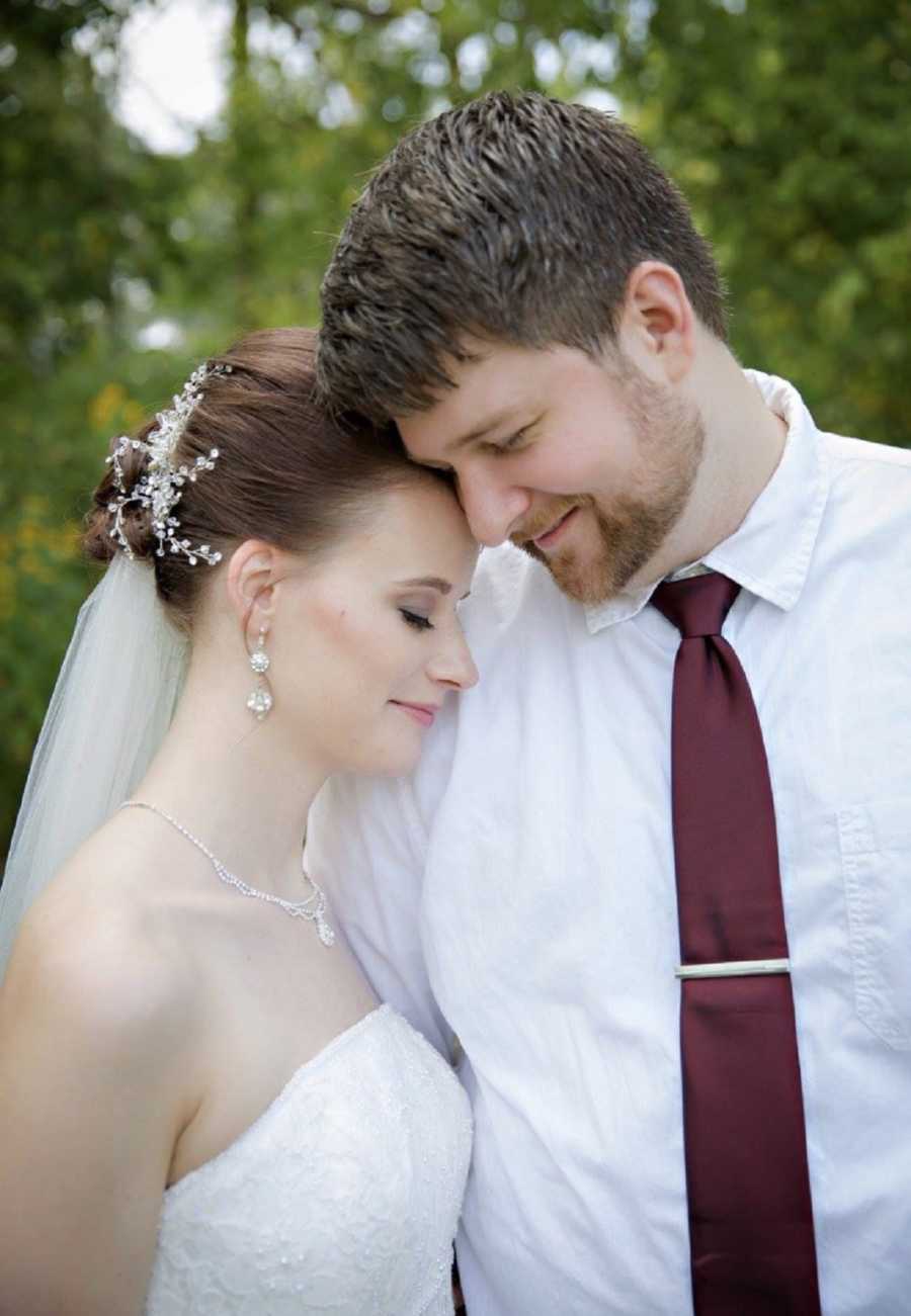 Bride and groom stand with heads touching outside