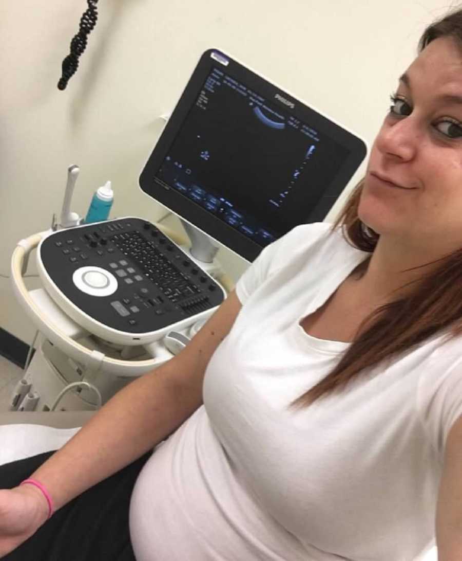 Pregnant woman smiles as she takes selfie with ultrasound machine