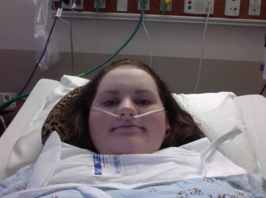 Young woman who tried to commit suicide lays in hospital bed on oxygen smiling