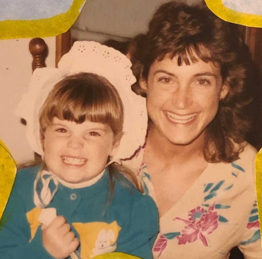 Mother smiles beside young daughter who has bonnet on her head