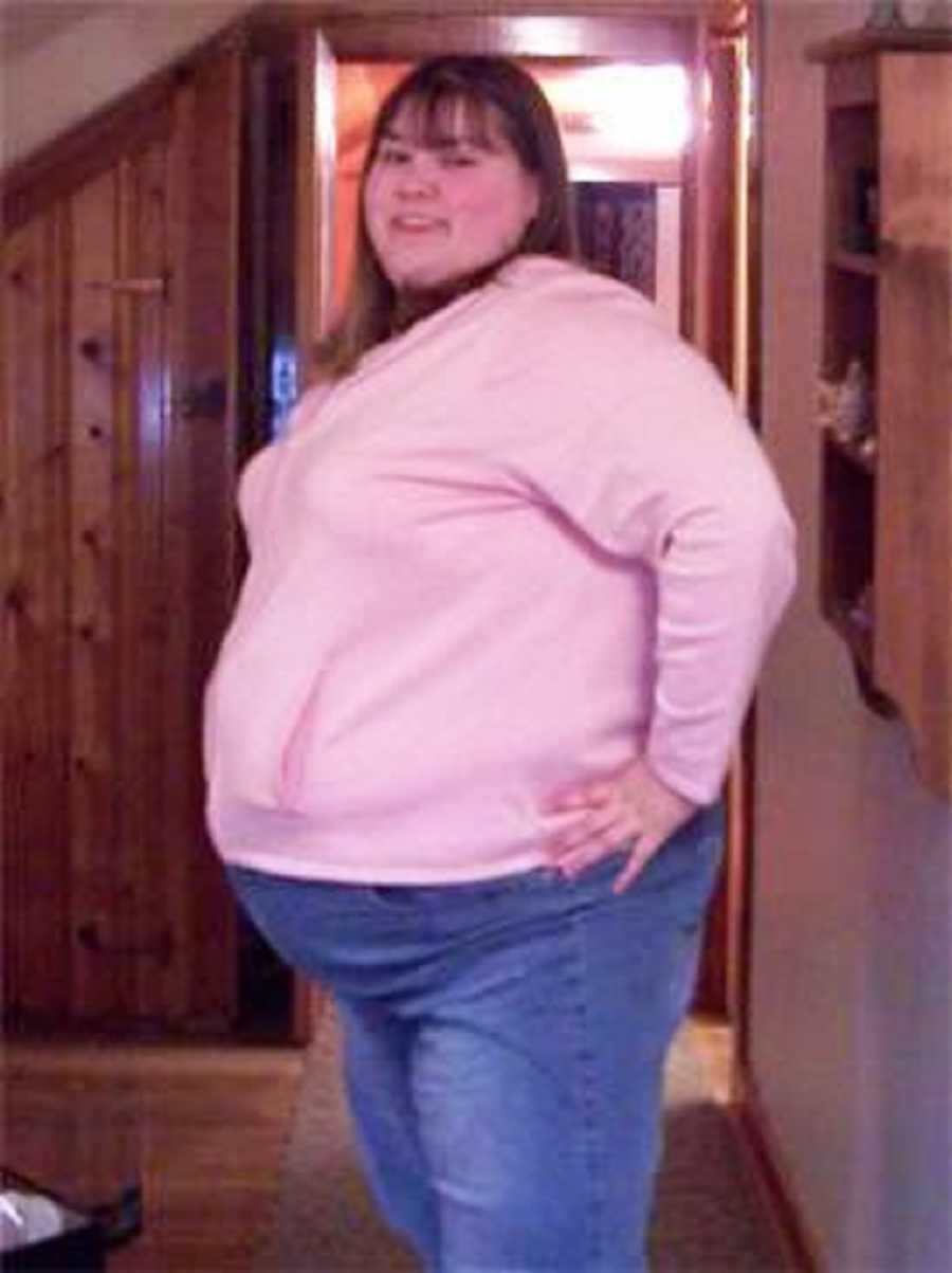 Overweight teen smiles as she stands in home with hands on her hips