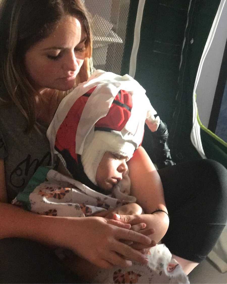 Mother looks down at son with Williams Syndrome who sits on her lap with foam helmet on