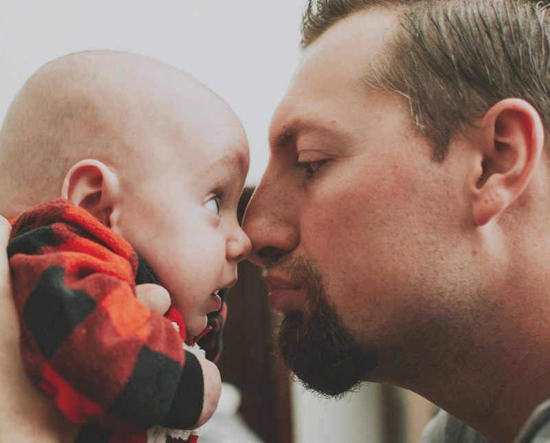 Father holds up baby boy close to his face