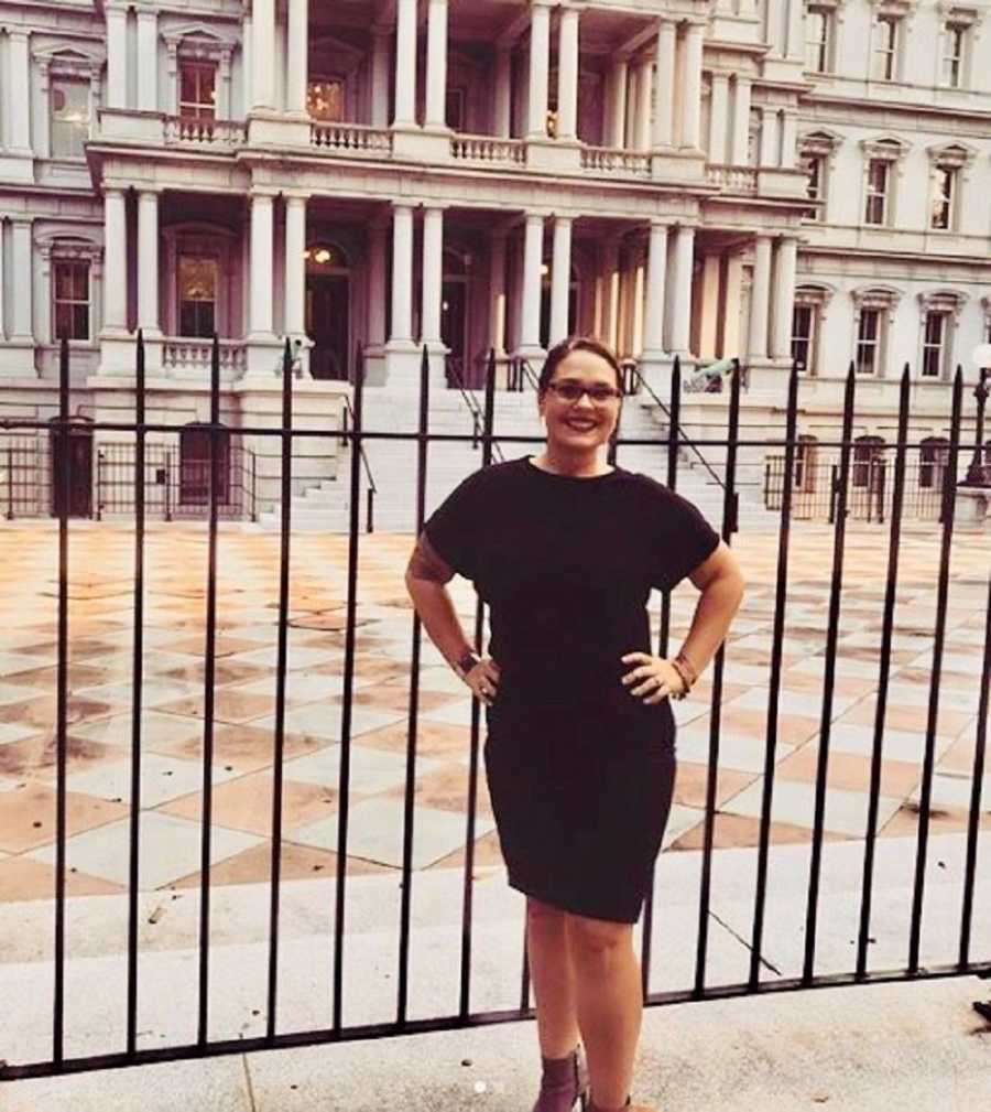 Woman who was kidnapped and abused stands smiling with hands on her hips in front of court building