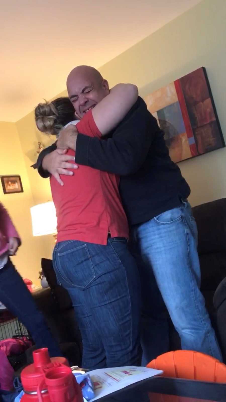 Man stands in home as he hugs his kidney donor