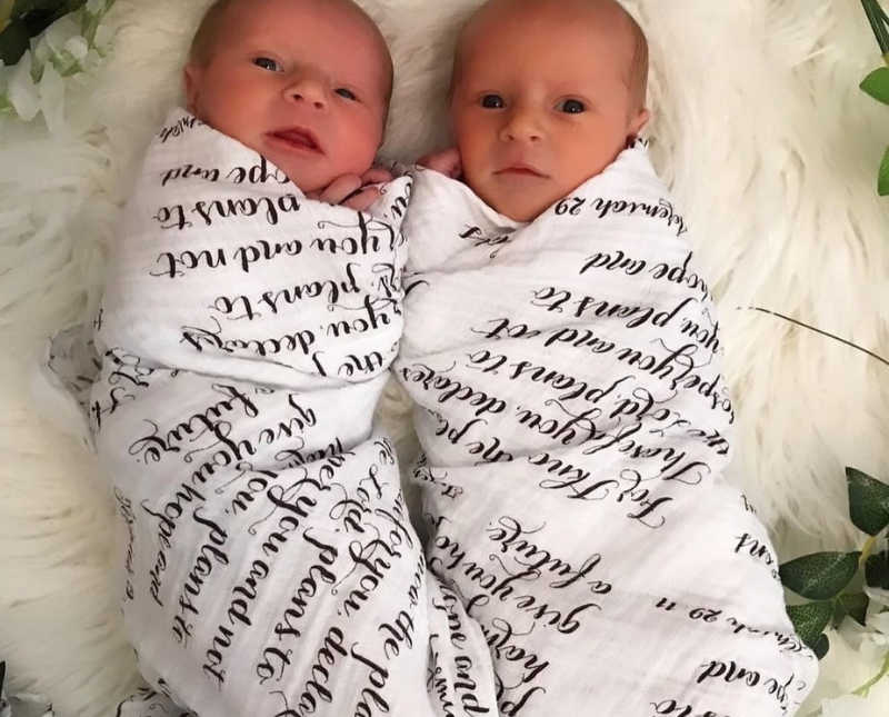 Twin newborns lay on their backs swaddled in blankets