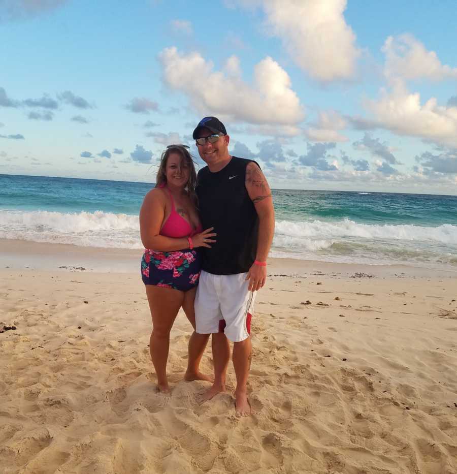 Woman who has always wanted to be pregnant stands with husband on beach