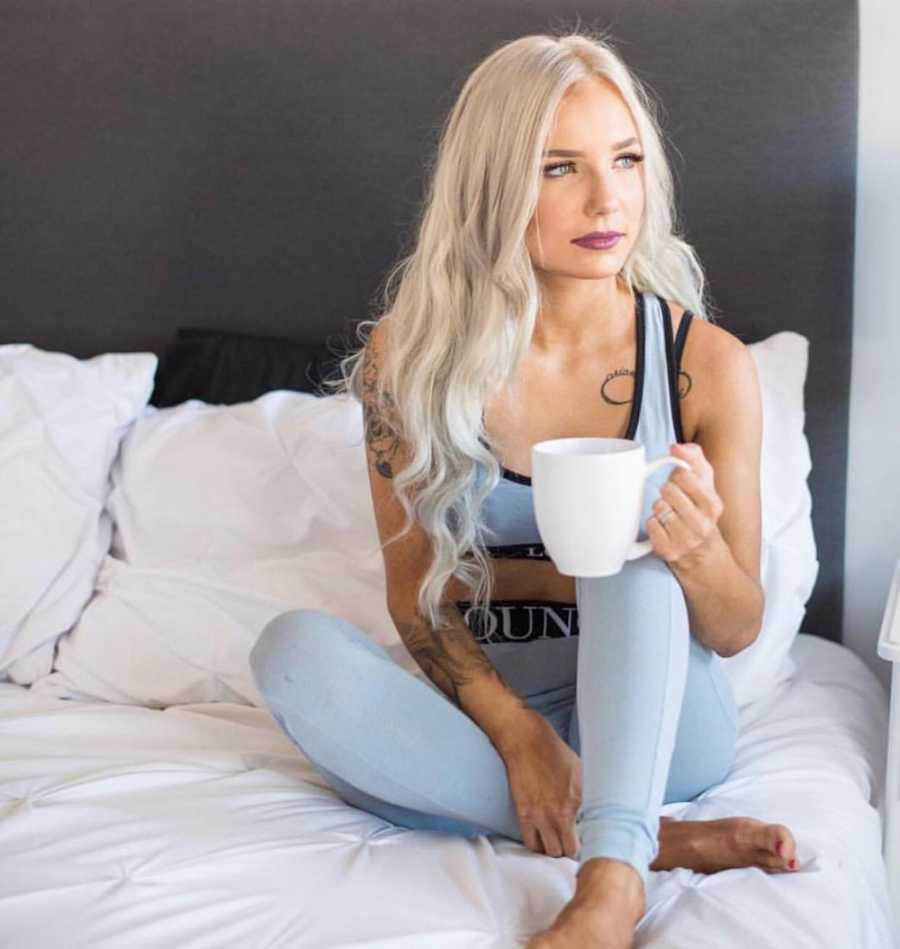 Woman who became Instagram famous sits on bed holding cup of coffee