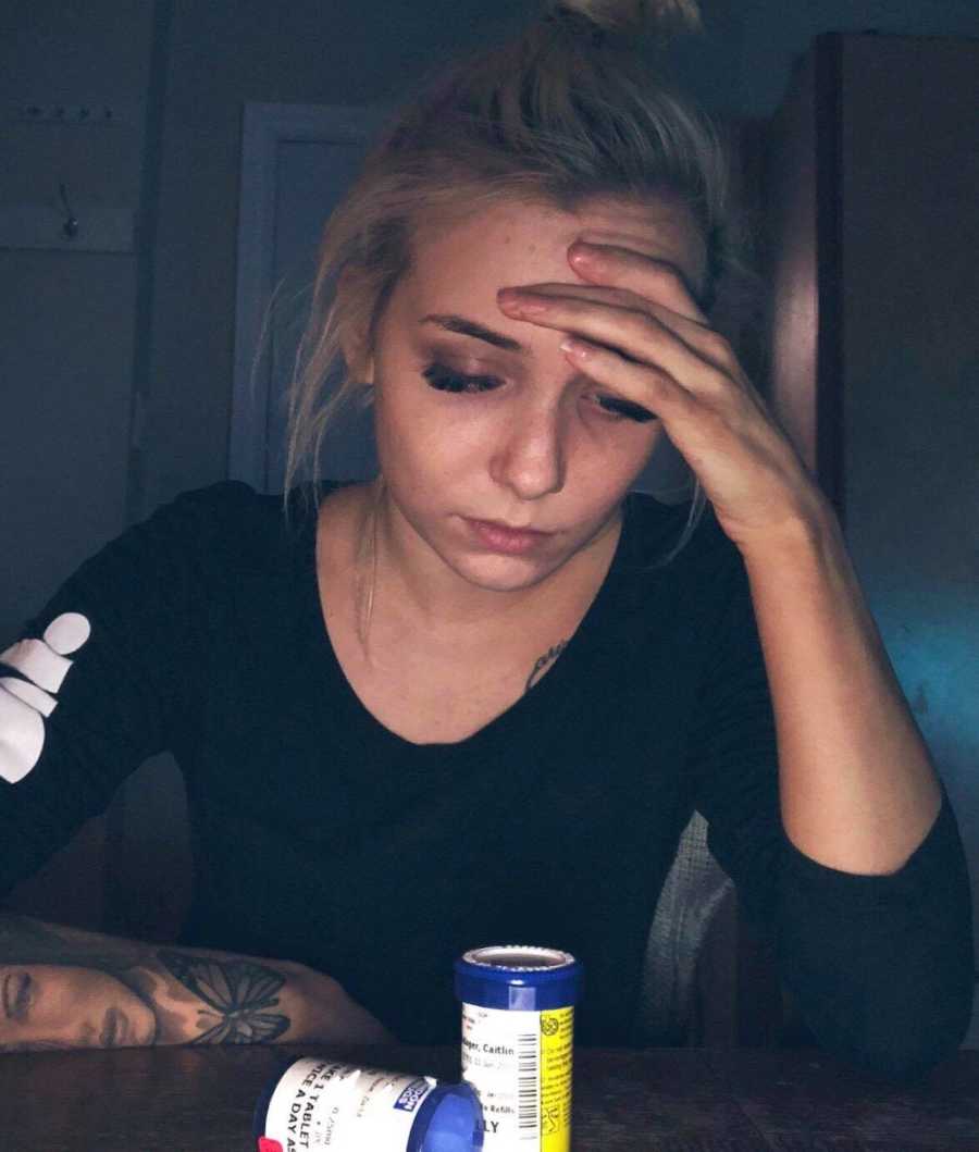 Woman who was stressed about looking perfect on Instagram resting head on hand with two pill bottles in front of her