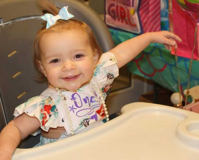 Little girl smiles as she sits in high chair