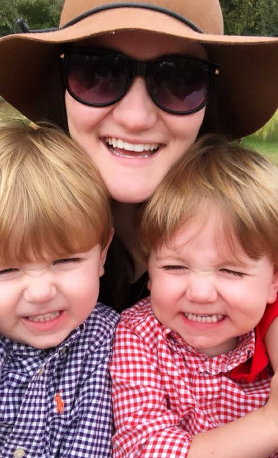 Mother smiles in selfie with young twin boys