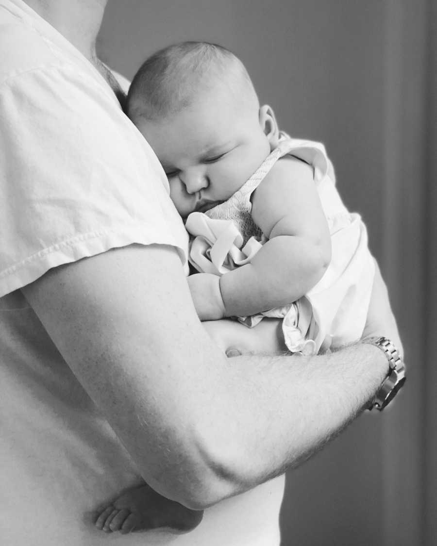Baby is asleep in arms of her father