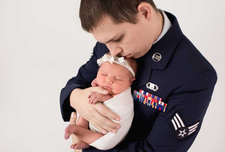 Father who is in air force stands in uniform holding baby girl with Aicardi Syndrome