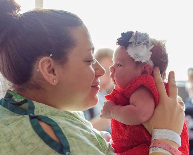 Mother smiles as she holds up newborn to her face