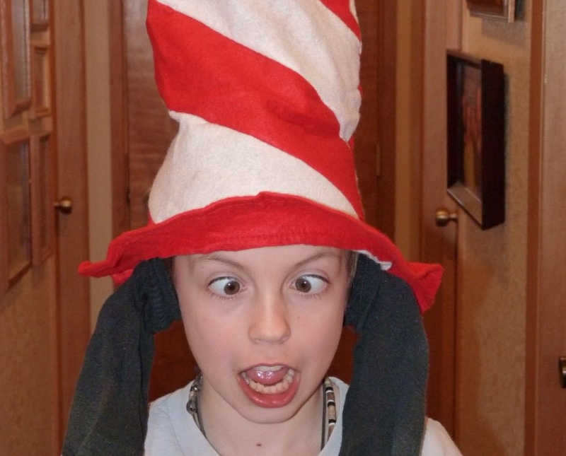 Little boy with ADHD stands in home with candy cane hat on and socks on his ears