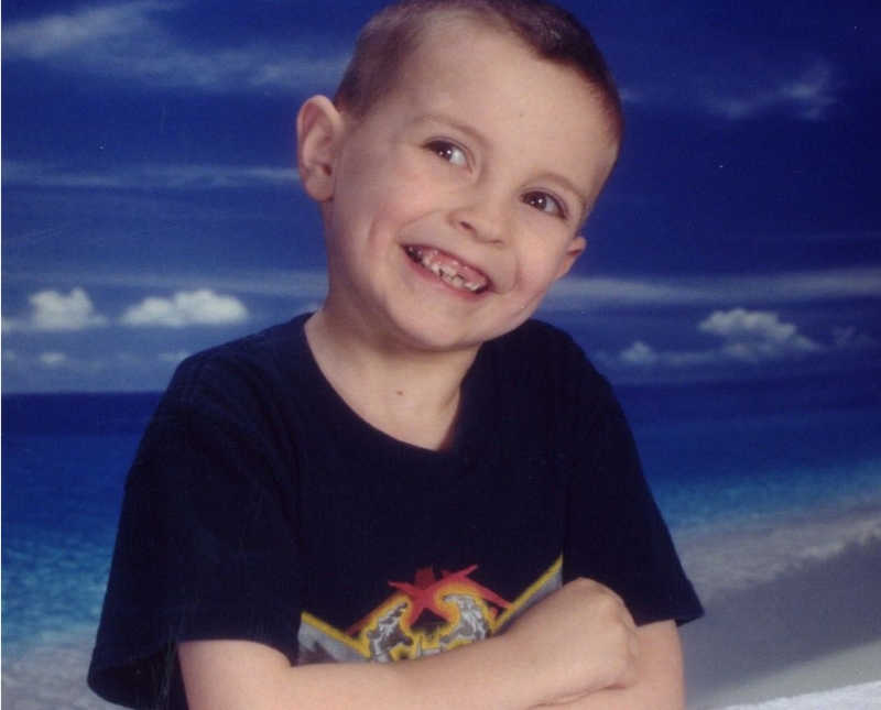 Little boy with ADHD smiles for school picture with beach background