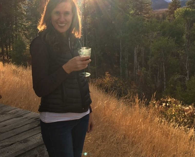 Woman whose husband had an affair stand outside in field holding glass of wine
