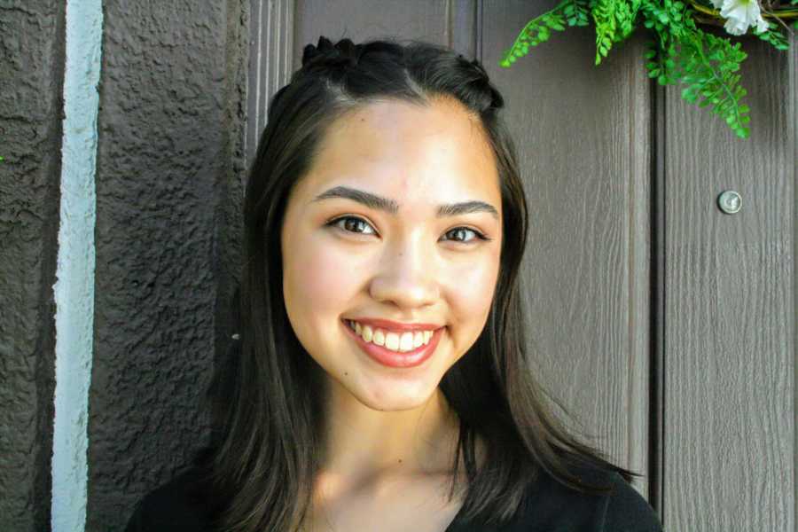 Young asian girl who struggled growing up with predominately white people stands outside smiling 