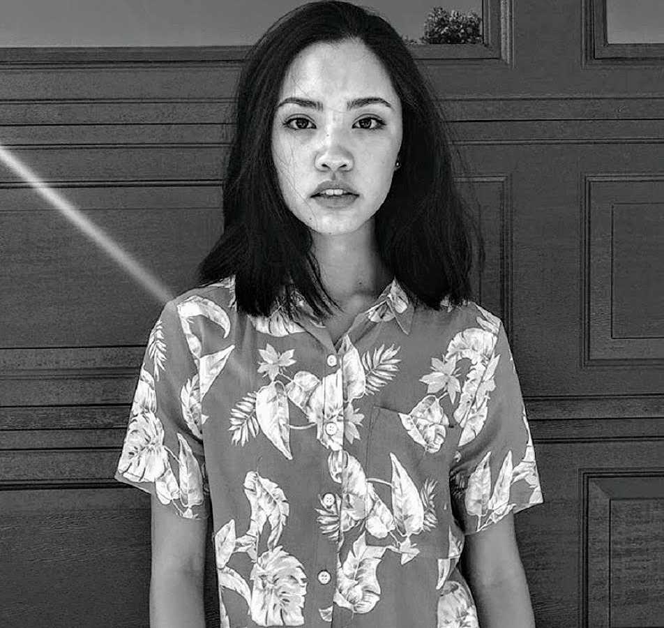 Teen who struggled growing up in predominately white community stands in front of garage door in Hawaiian shirt