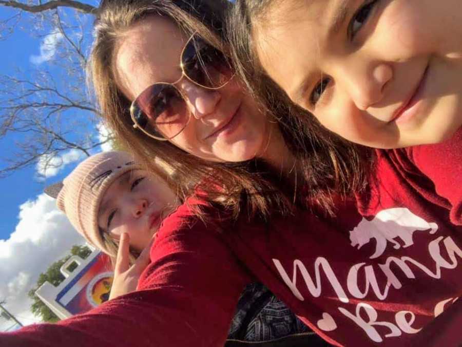Woman who was switched at birth smiles in selfie outside with her two daughters