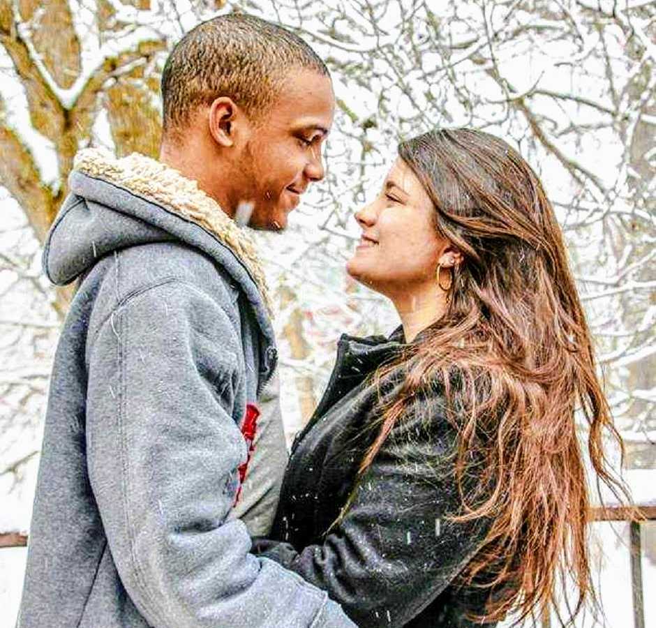 Mixed race couple stand outside in snowy weather looking into each others eyes
